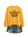 Flat lay of ginger yellow sweatshirt with Youngest Sister text and ripped denim shorts - Yellow (Black Font)