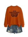 Detail of orange sweatshirt with sister slogan paired with distressed blue denim shorts - Burnt Orange (Black Font)