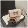 Close-up of pink mini chain bag featuring a large silver metal bow on glossy patent leather - Pink