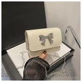 Detail of a creamy white mini square bag with a silver metal bow and fine chain strap - White