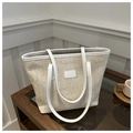 Close-up of beige woven tote bag with white leather straps on a glass table - White