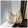 Detail of creamy white tote with cloud pleat texture and embossed logo on wood surface - White Without Pendant