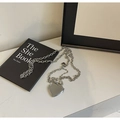 Detail der silbernen Herzkette auf Marmoroberfläche mit Büchern im Hintergrund - Kette