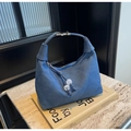 Detail of blue denim crescent bag featuring diamond quilting and beaded zipper pull - Dark Blue