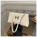 Close-up of white pleated shoulder bag with a silver metal bow buckle and fine texture - White
