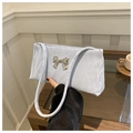 Detailed close-up of a light blue pleated shoulder bag with a silver metal bow accent - Blue