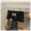Detail of black rectangular underarm bag featuring a silver metal bow and pleated texture - Black