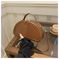 Detail of brown chevron quilted crescent handbag with gold zippers on a wooden table - Brown
