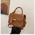 Detail view of a dark brown crossbody square bag featuring a metal twist lock and top handle - Brown