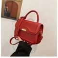 Close-up of red leather handbag showing gold twist lock and Fashion & Bag tag - Red