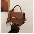 Close-up of brown leather crossbody bag with vintage golden spiral lock and leather tag - Brown