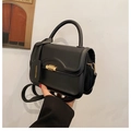 Detail of matte black square handbag featuring golden spiral lock and fashion tag - Black