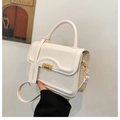 Detail of white leather crossbody bag showing golden buckle and fashion brand tag - White