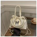 Gros plan du sac seau blanc iridescent avec chaîne de perles et détail papillon - Blanc Cassé