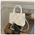 White quilted denim handbag with frayed edges and circular handle shown in a cafe setting - White