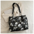 Detail of floral skull print shoulder bag with metal rings on beige blazer background - Black