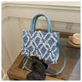 Detail of light blue denim tote with quilted raw edge patterns and stylish top handles - Blue