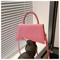 Detail of pink heart-quilted crossbody bag with braided handle and gold hardware - Pink