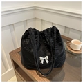 Dettaglio borsa tote nera plissettata con fibbia a fiocco argento su tavolo in legno - Nero