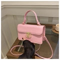 Detailed macro view of pink crocodile embossed leather bag with gold metal clasp - Pink
