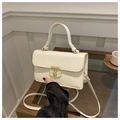 Detail of cream crocodile embossed handbag with gold geometric clasp on a wooden table - Off White