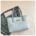 Dettaglio macro della borsa tote azzurra con ricami ondulati e rinforzi in rivetti metallici - Tipo standard / Blu