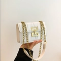 White quilted flap bag with gold hardware lock and chain strap held by hand - White