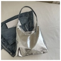 Vista dettagliata di una borsa tote argento metallizzato lucido su tessuto bianco - Argento