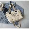 Beigefarbene Canvas-Einkaufstasche mit Buchstabendruck und braunen Lederakzenten - Khaki