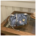 Detalle de bolso tipo cubo en denim azul con parches de corazones en mesa madera - Azul