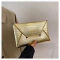 Detail shot of golden crocodile texture and metallic bar buckle on elegant clutch bag - Gold
