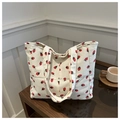 Detailed view of cream corduroy tote bag with red strawberry pattern on wooden table - White