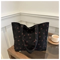 Detail of black corduroy tote bag with red strawberry pattern and soft ribbed texture - Black