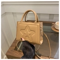 Dettaglio della piccola borsa kaki con stella goffrata su un tavolo da caffè con tazza - Cachi