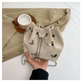Beige bucket bag with butterfly studs, pearl drawstring, and silver chain strap - Light Khaki