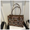 Detail of colorful geometric woven tote bag with brown faux leather straps on a white book - Coffee