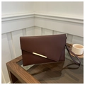 Close-up of burgundy envelope clutch bag with gold metal buckle on a glass table - Brown