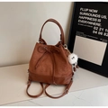 Detalle de bolso tipo cubo en terciopelo marrón con cordón y pompón de peluche - Café con Colgante
