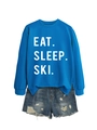 Close-up of Eat Sleep Ski print on blue cotton sweatshirt with distressed denim shorts - Lake Blue (White Font)
