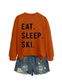Flat lay of an orange cotton sweatshirt with black Eat Sleep Ski print and denim shorts - Burnt Orange (Black Font)