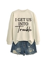 Detail eines beigen Sweatshirts mit I GET US INTO TROUBLE Aufdruck und Rippbündchen am Hals - Sandfarbenes Sweatshirt (Schwarze Schrift)