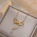 Collana con fiocco dorato con zirconi e pendente a goccia su una scatola per gioielli - Collana con Fiocco in Zirconia (X1844)
