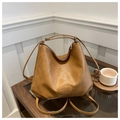 Close-up of brown faux leather tote with textured finish and brand logo on a glass table - Brown