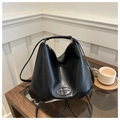 Detail of minimalist black hobo bag on coffee table featuring branded oval leather patch - Black
