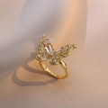 Anello a farfalla dorato con zirconi brillanti su un tessuto strutturato rosa cipria - Anello a Farfalla Dorato (J064)