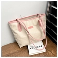 Detalle de bolso tote crema con relieve de estrellas y costuras rosas en contraste - Blanco Leche & Rosa