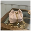 Pink drawstring bucket bag with gold chain and pearl accents on a wooden table - Pink