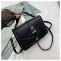 Fashionable black crossbody mini bag with gold buckle on a stylish white fabric background - Black