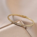 Elegante bracciale rigido dorato con fila di zirconi quadrati e chiusura laterale sicura - Bracciale in Zirconi (TS0111)