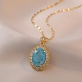 Elegante collar de titanio dorado con gema ovalada azul grande y halo de circonitas - Estilo Azul (X1053)